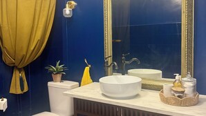 Ein Badezimmer mit einer weißen Toilette, einem Waschbecken mit Spiegel und einer blauen Wand.