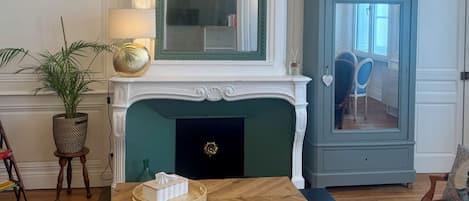 A living room with a fireplace, a chandelier, a blue cabinet, and a wooden coffee table.