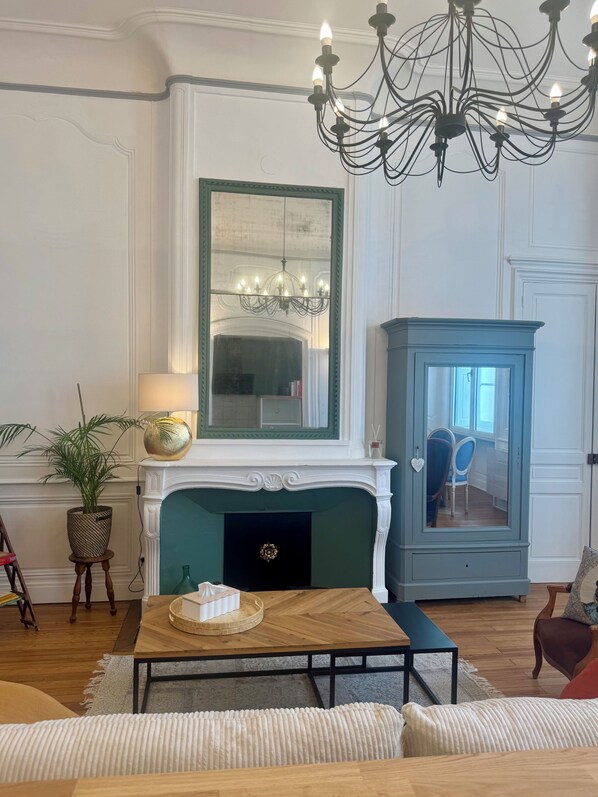 A living room with a fireplace, a chandelier, a blue cabinet, and a wooden coffee table.