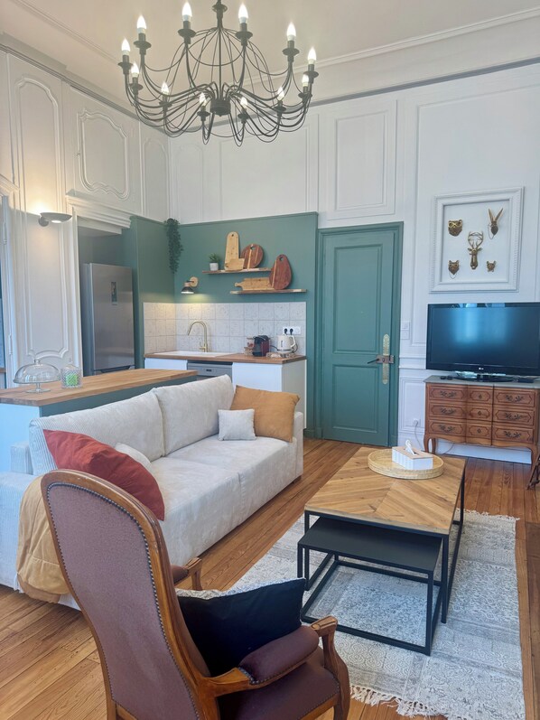 Uma sala de estar moderna com sofá, mesa de centro de madeira, televisão e área de jantar com porta verde.
