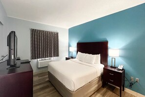 A hotel room with a bed, two bedside lamps, a TV, and a window with curtains. - 1 King Bed | Non-Smoking, Micfridge (Tiffin)