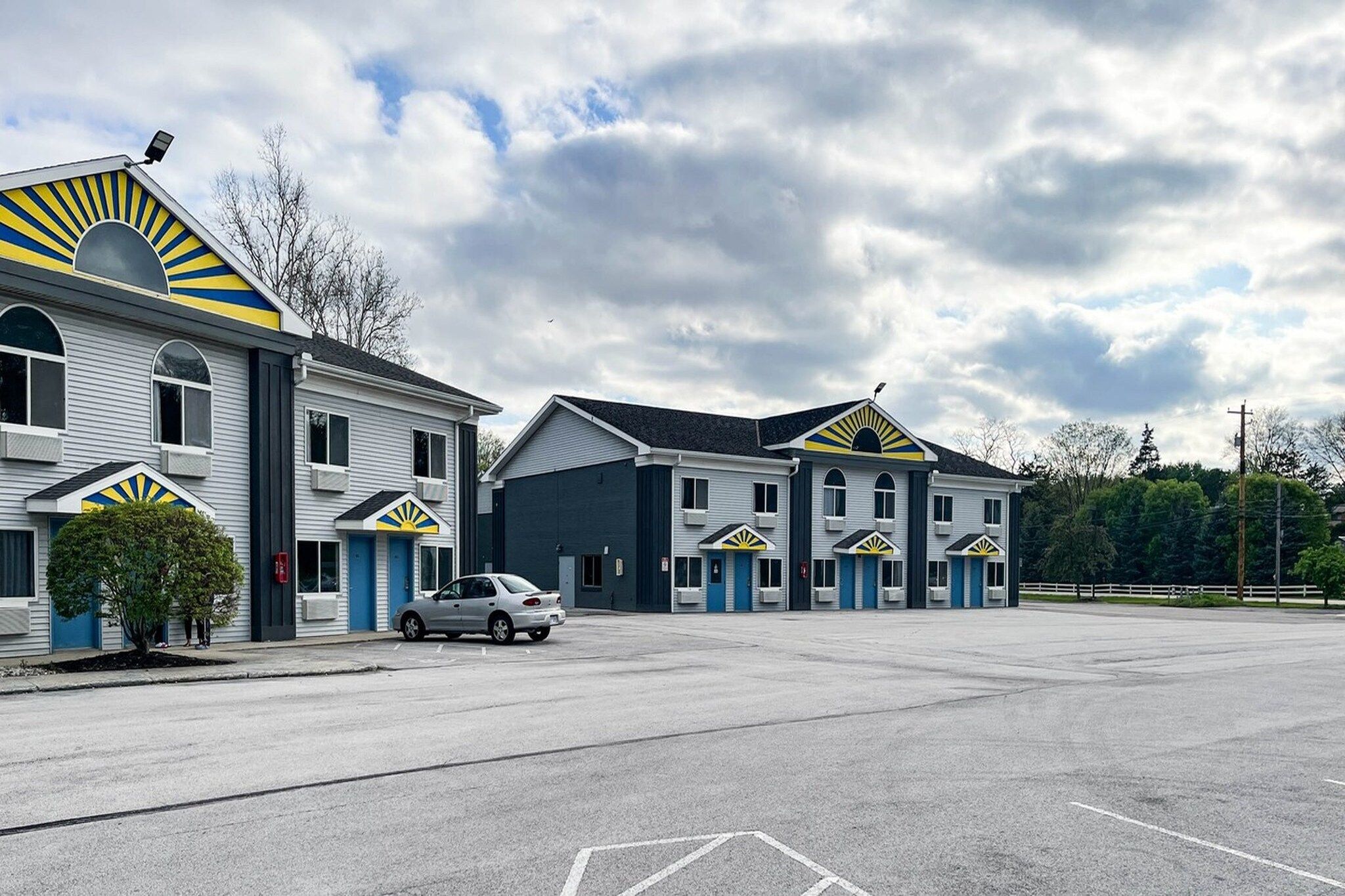 A motel with multiple units, a parking lot, and a clear sky.