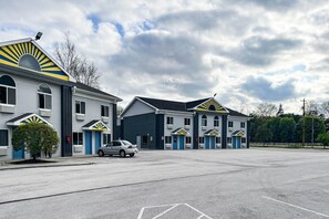 A motel with multiple units, a parking lot, and a clear sky. - 1 King Bed | Non-Smoking, Micfridge (Tiffin)