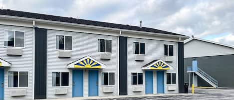 Ein Motel mit einer Reihe von Zimmern, jedes mit einer blauen Tür und einem Sonnensymbol darüber.