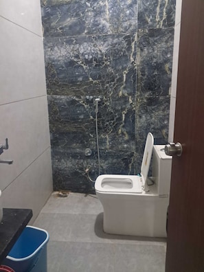 A bathroom with a toilet, a shower, and a sink. - Om Mukunda Homestay (Ujjain)