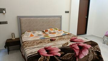 Quarto com cama, mesa de cabeceira, tomada e porta.