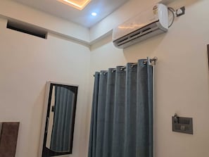 A bathroom with a shower curtain, an air conditioning unit, and a light fixture. - Om Mukunda Homestay (Ujjain)