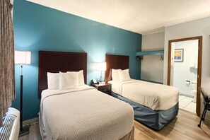A hotel room with two beds, a nightstand, a lamp, and a bathroom visible through an open door. - 2 Full Beds | Non-Smoking, Hot Tub (Tiffin)