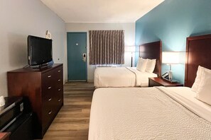 A hotel room with two beds, a TV on a dresser, a desk with a lamp, and a window with curtains. - 2 Full Beds | Non-Smoking, Hot Tub (Tiffin)