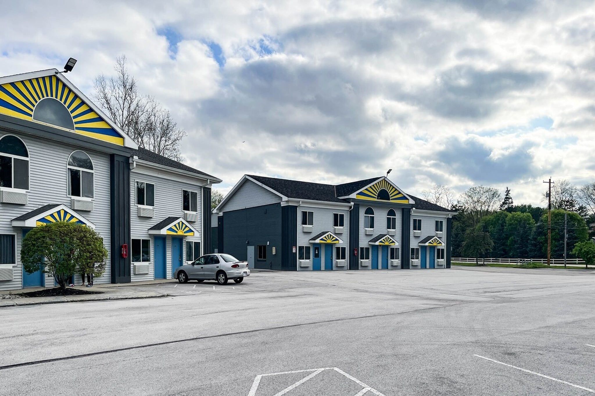Un motel con varias habitaciones, un estacionamiento y cielo despejado.