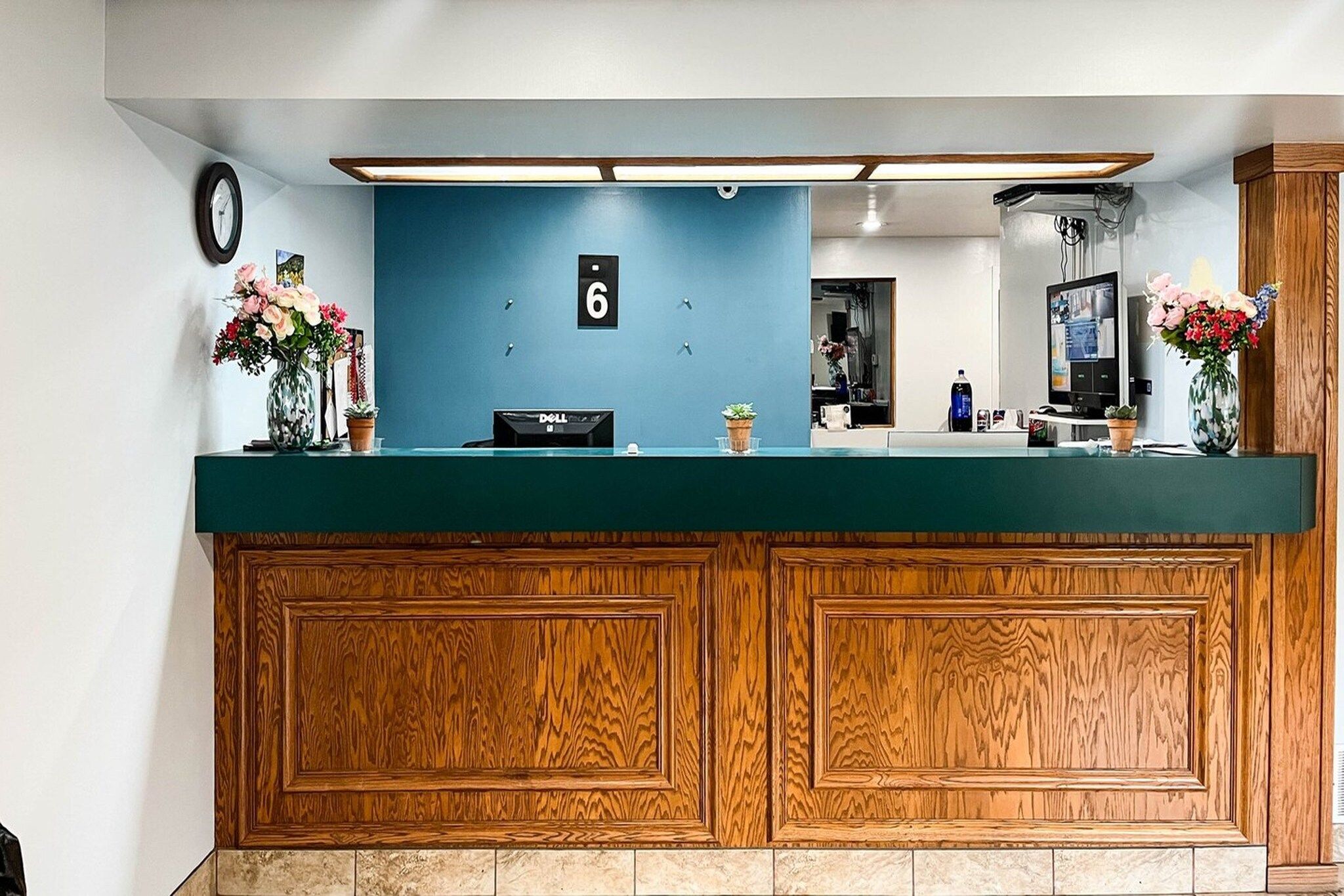 Una mesa de recepción con pared azul, paneles de madera, un reloj y un letrero con el número 6.