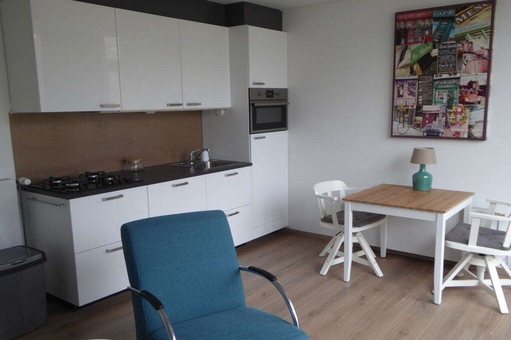 A compact kitchen with white cabinets, a microwave, and a small dining area with a table and two chairs.