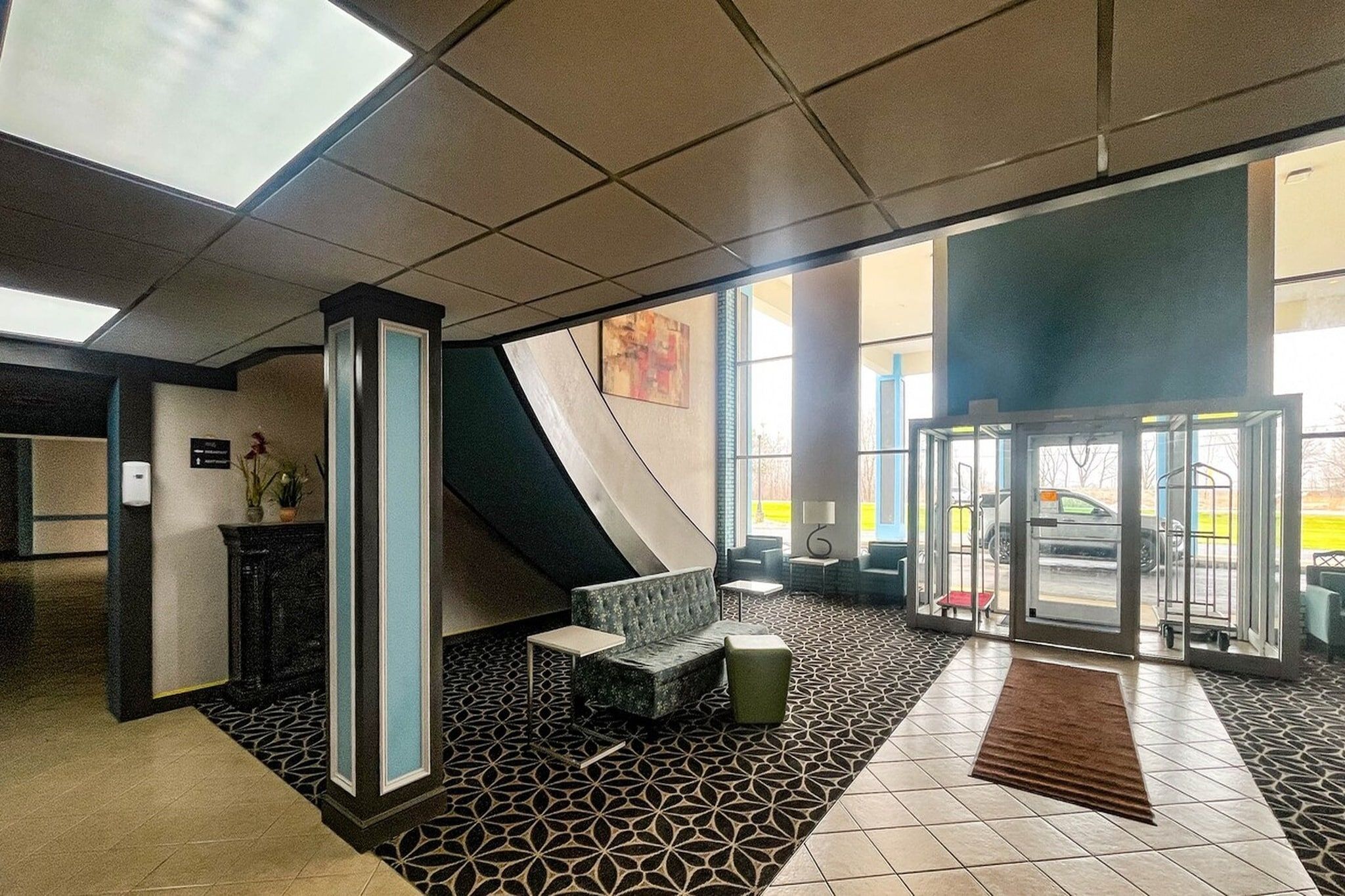 Vestíbulo con recepción, zona de estar y puerta de vidrio.