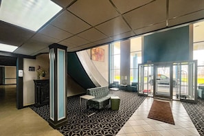 A lobby with a reception desk, seating area, and a glass door entrance.