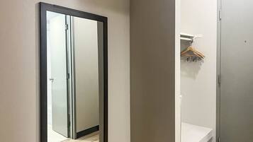 A hallway with a sliding door, a white wall, and a wooden hanger on a white shelf.