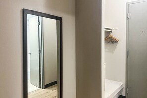 A hallway with a sliding door, a white wall, and a wooden hanger on a white shelf.