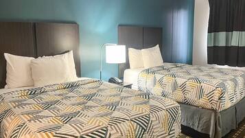 Een hotelkamer met twee bedden, een nachtkastje met een lamp en een raam met gordijnen.
