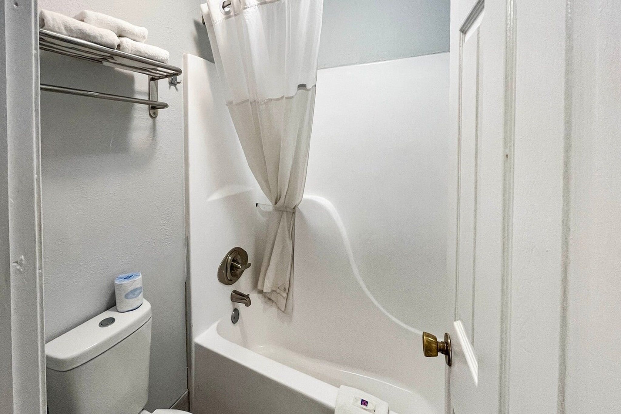 A small, enclosed bathroom with a bathtub, a toilet, and a shower curtain.
