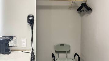 A medical examination room with a wheelchair, a hair dryer, and a coat rack.