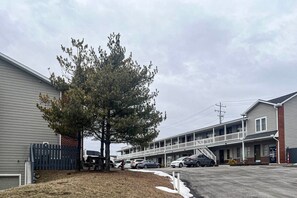 A motel with a parking lot, a tree, and a building with a balcony.