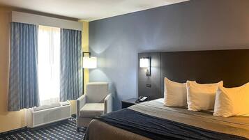 Ein Hotelzimmer mit einem Bett, einem Sessel, einem Nachttisch mit Lampe und einem an der Wand befestigten Telefon.