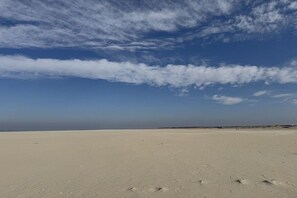 Ein weiter, sandiger Strand mit blauem Himmel und weiter Ferne.