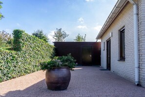 A paved walkway leading to a building with a brick facade and a large planter with greenery. - North Sea Park Ouddorp - Müntefehr (Ouddorp)