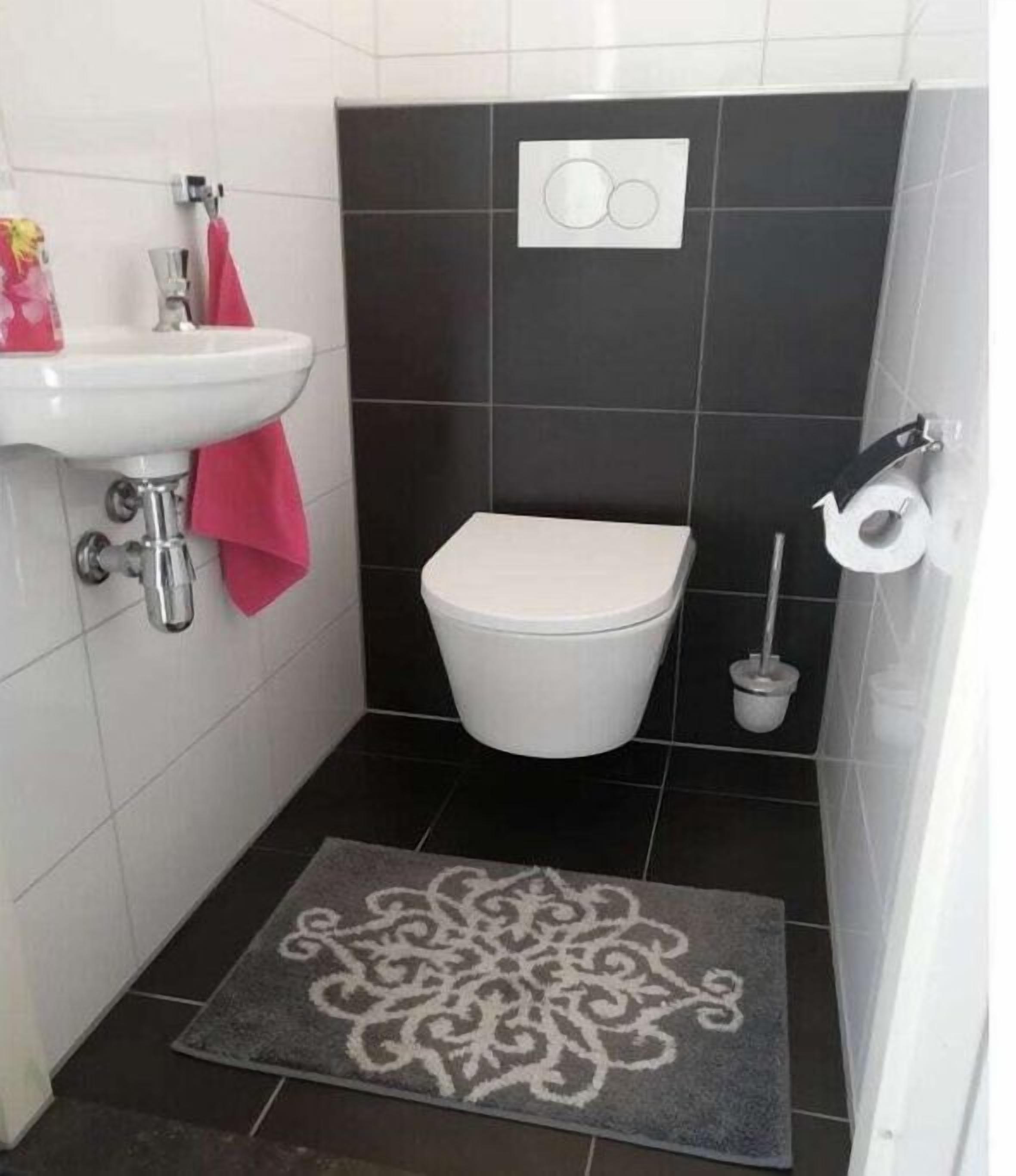 A small bathroom with a white sink, a toilet, and a bidet.
