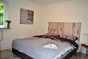 Ein Schlafzimmer mit einem Bett, einem Holzkopfteil, einem an der Wand befestigten Schild und einem Fenster mit Jalousien.