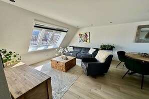A modern living room with a sofa, coffee table, and a dining area. - Holiday apartment with 2 bedrooms (Limmen)