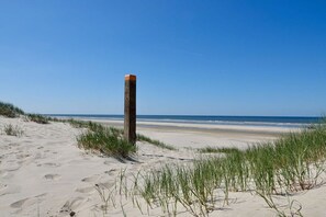 A sandy beach with a wooden post and grass in the foreground. - Holiday apartment with 2 bedrooms (Limmen)