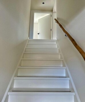 A white staircase with a wooden handrail leading to a door at the top. - Holiday apartment with 2 bedrooms (Limmen)