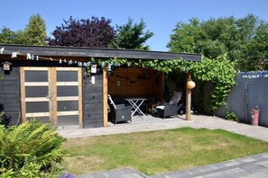 Une cabane en bois dotée d’un patio, d’un barbecue et de mobilier d’extérieur.