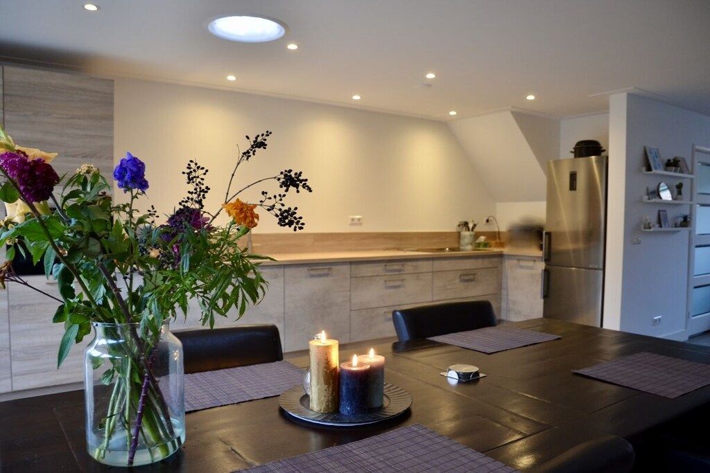 Une cuisine moderne avec une table à manger pour deux personnes, agrémentée d’un vase de fleurs et de bougies.