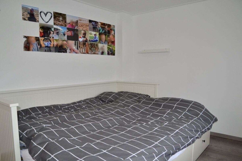 Une chambre à coucher avec un lit, un collage de photos accroché au mur et un radiateur blanc.