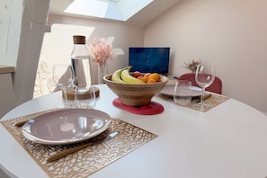 A dining table with a bowl of fruit, two wine glasses, and a plate. - Le Nid Poudré par Your Sweet Loc (Venette)