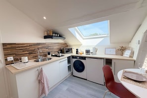A compact kitchen with a built-in dishwasher, a microwave, and a small window above the sink.