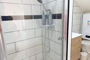 A modern bathroom with a glass-enclosed shower, white tiles, and a wooden vanity. - Le Nid Poudré par Your Sweet Loc (Venette)