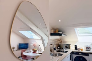 A modern kitchen with a skylight, a dining area with a table and chairs, and a built-in washing machine.