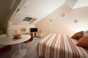 A compact bedroom with a bed, a desk, and a television. - Le Nid Poudré par Your Sweet Loc (Venette)