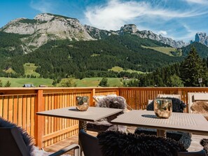 A wooden deck with tables and chairs, overlooking a mountainous landscape with a clear sky. - Cabin in Annaberg With Swimming Pool (Annaberg-Lungoetz)
