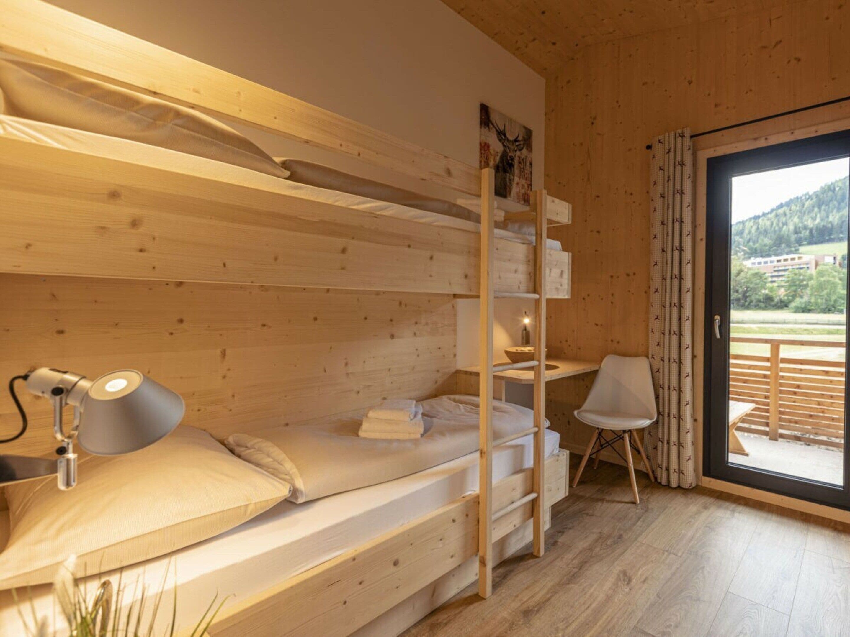 Un interior de madera con literas, un escritorio y una silla.