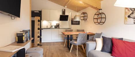 A modern living space with a wooden ceiling, a dining area, and a sofa with cushions.