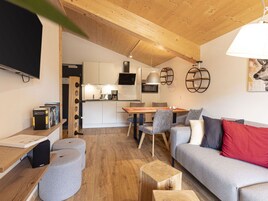 Un espacio de estar moderno con techo de madera, zona de comedor y sofá con cojines.