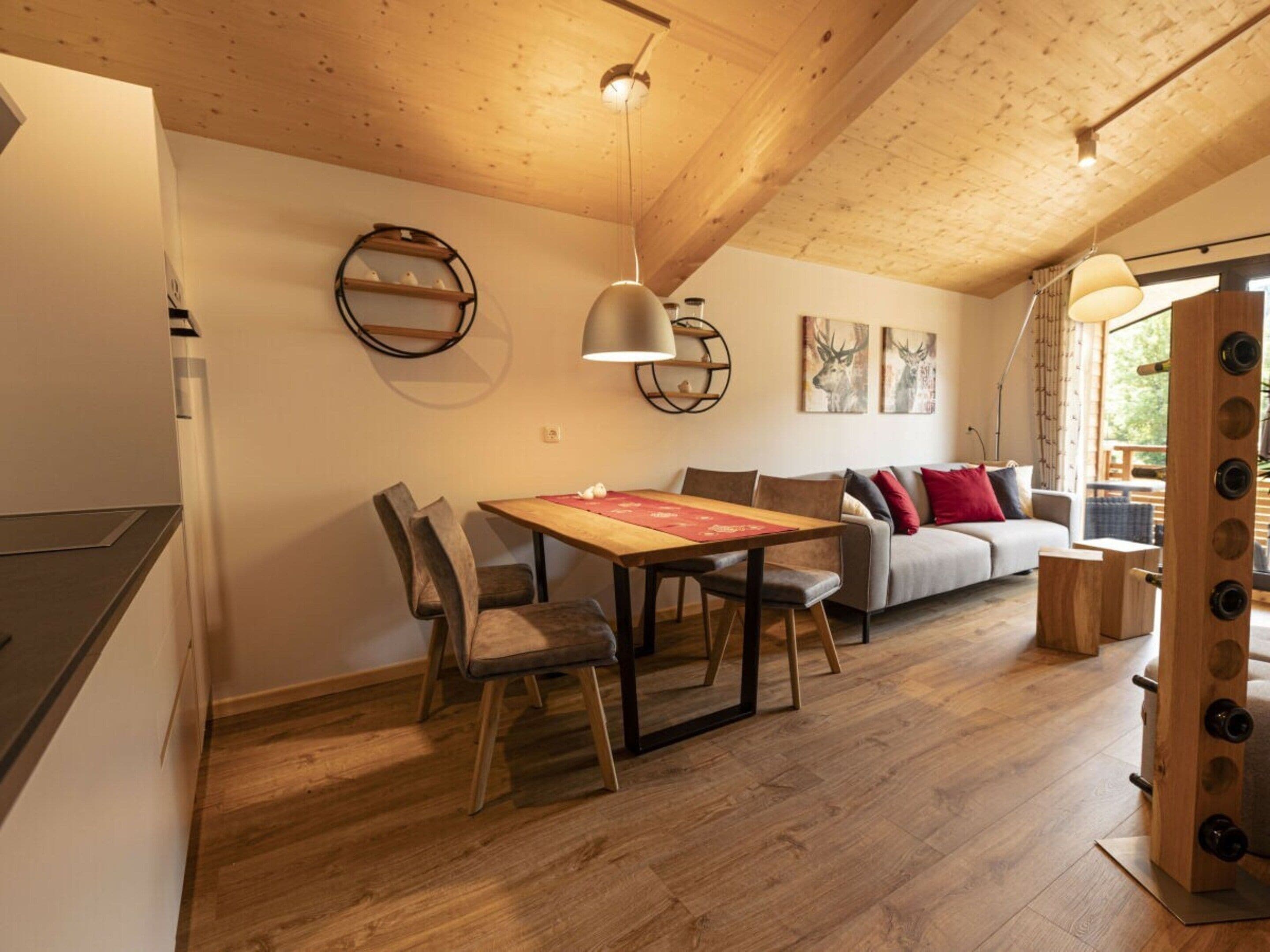 A cozy interior with a dining area, a sofa, and a wooden ceiling.