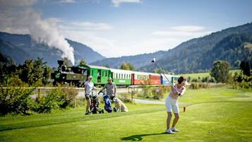 A golf course with a train in the background.