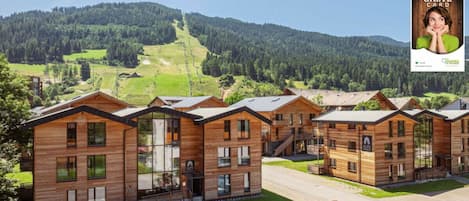 A row of modern wooden cabins with a ski slope in the background.
