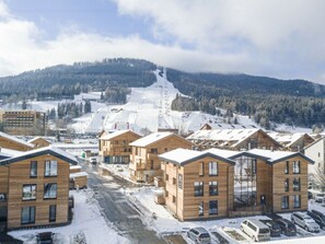 A snow-covered village with wooden buildings, a ski slope in the background, and a clear sky. - Apartment With 1 Bedroom (Sankt Georgen am Kreischberg)