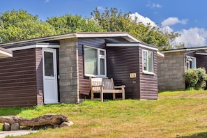 A small, single-story cabin with a front door, a window, and a bench outside.