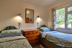 A bedroom with two beds, a dresser, a mirror, and a window with curtains.
